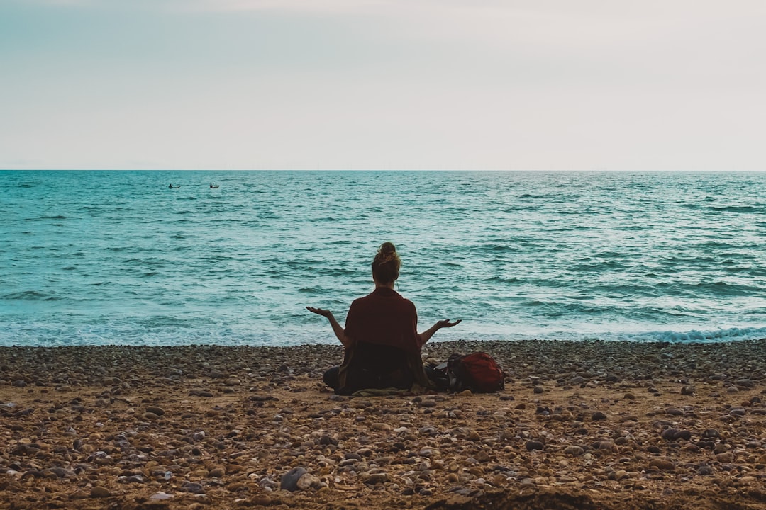 Woman practicing yoga on a peaceful shoreline at sunrise