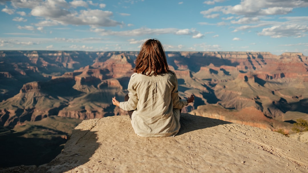 Woman sitting peacefully on a hillside overlooking distant mountains